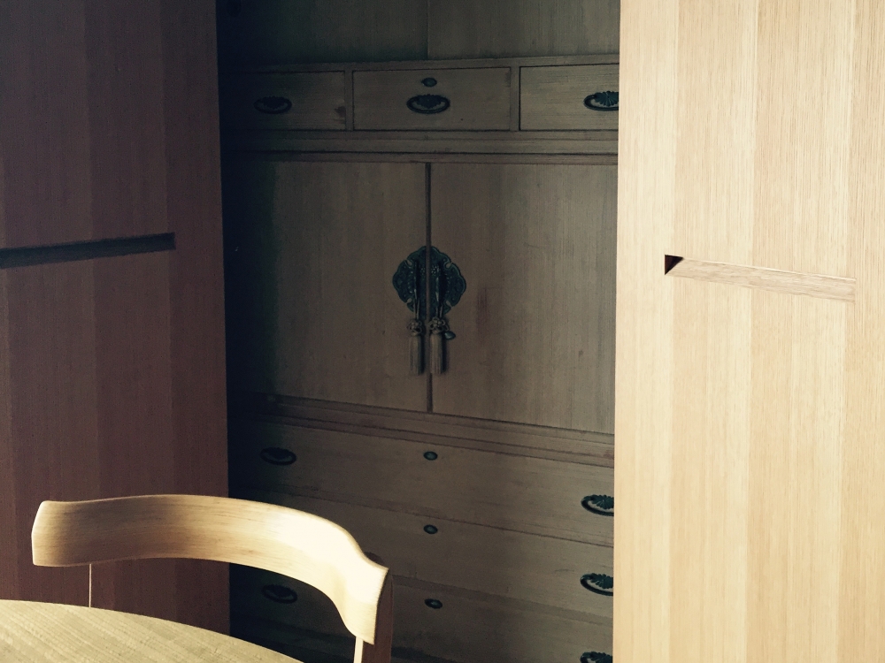  - リビングの壁一面にはタモでデザインした収納扉。&nbsp;&nbsp;中にはオーナーさまの何度かのお引越しでキズついた、桐の和ダンスが隠されています。&nbsp;&nbsp;「とても開けやすいんですよ」と喜んでくれた、まっすぐの取っ手。&nbsp;&nbsp;職人さんに叱られながらつくった甲斐がありました。&nbsp; -  - 